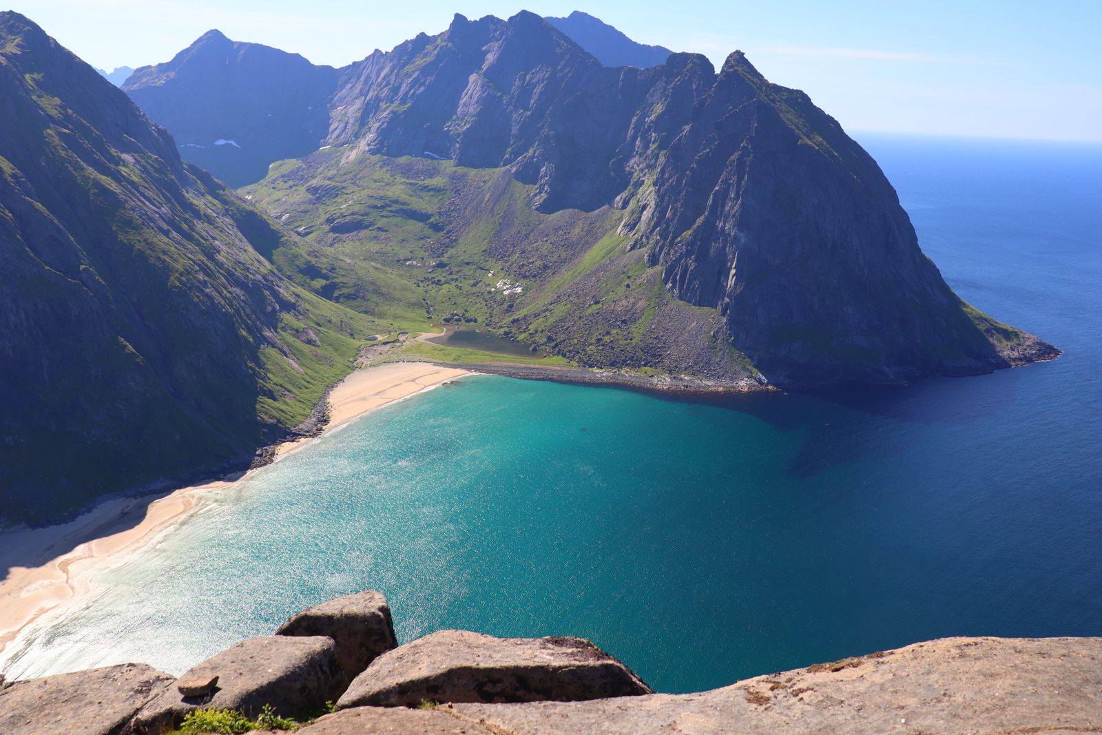 Plaża Kvalvika między zielonymi klifami